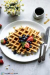 Homemade golden waffles with maple syrup, butter, and fresh berries
